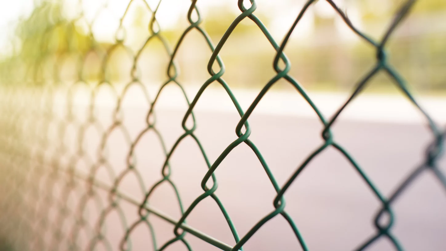 A close up of a chain link fence near construction equipment.
