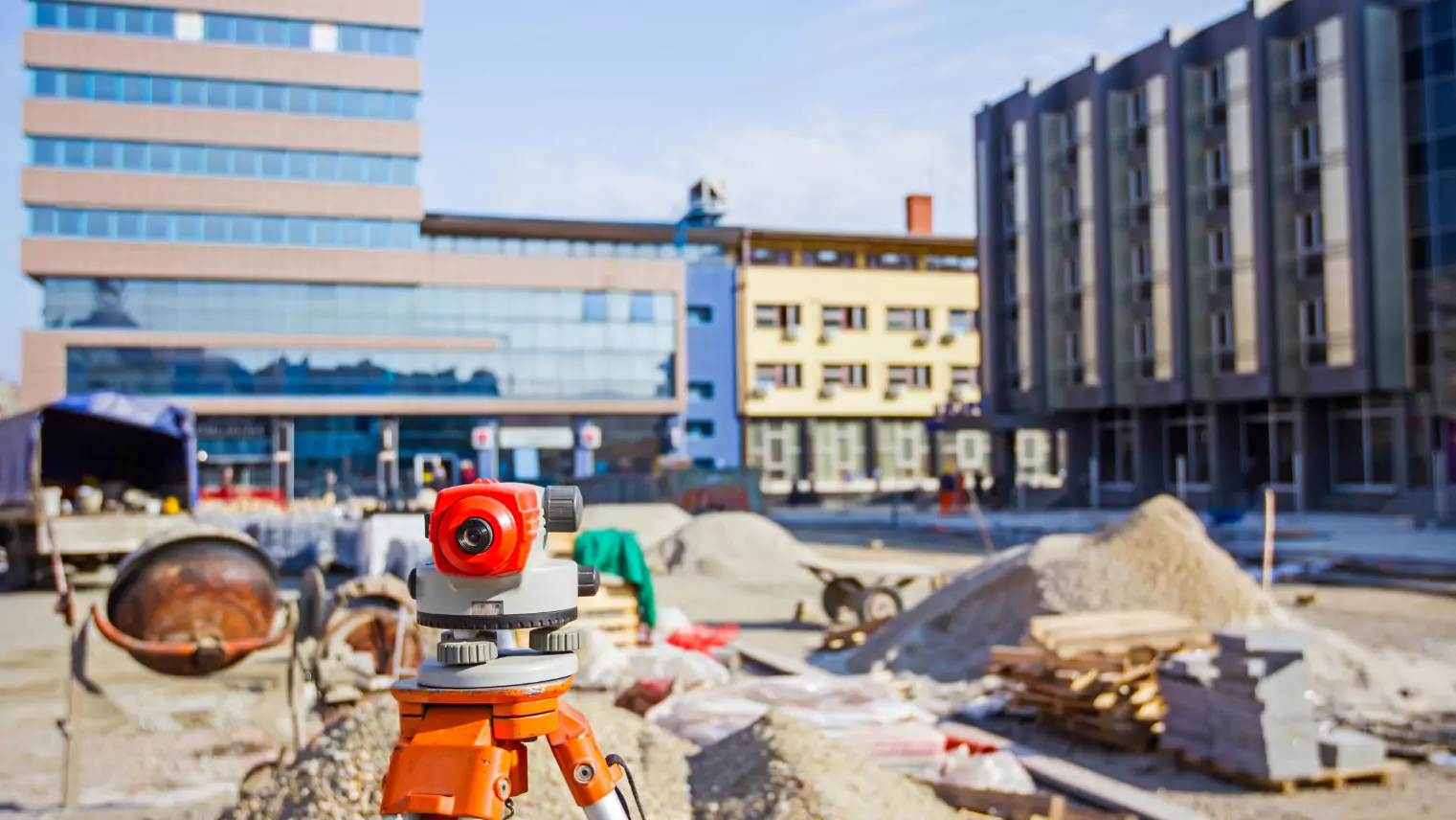 A construction worker is standing in front of construction equipment at a construction site.