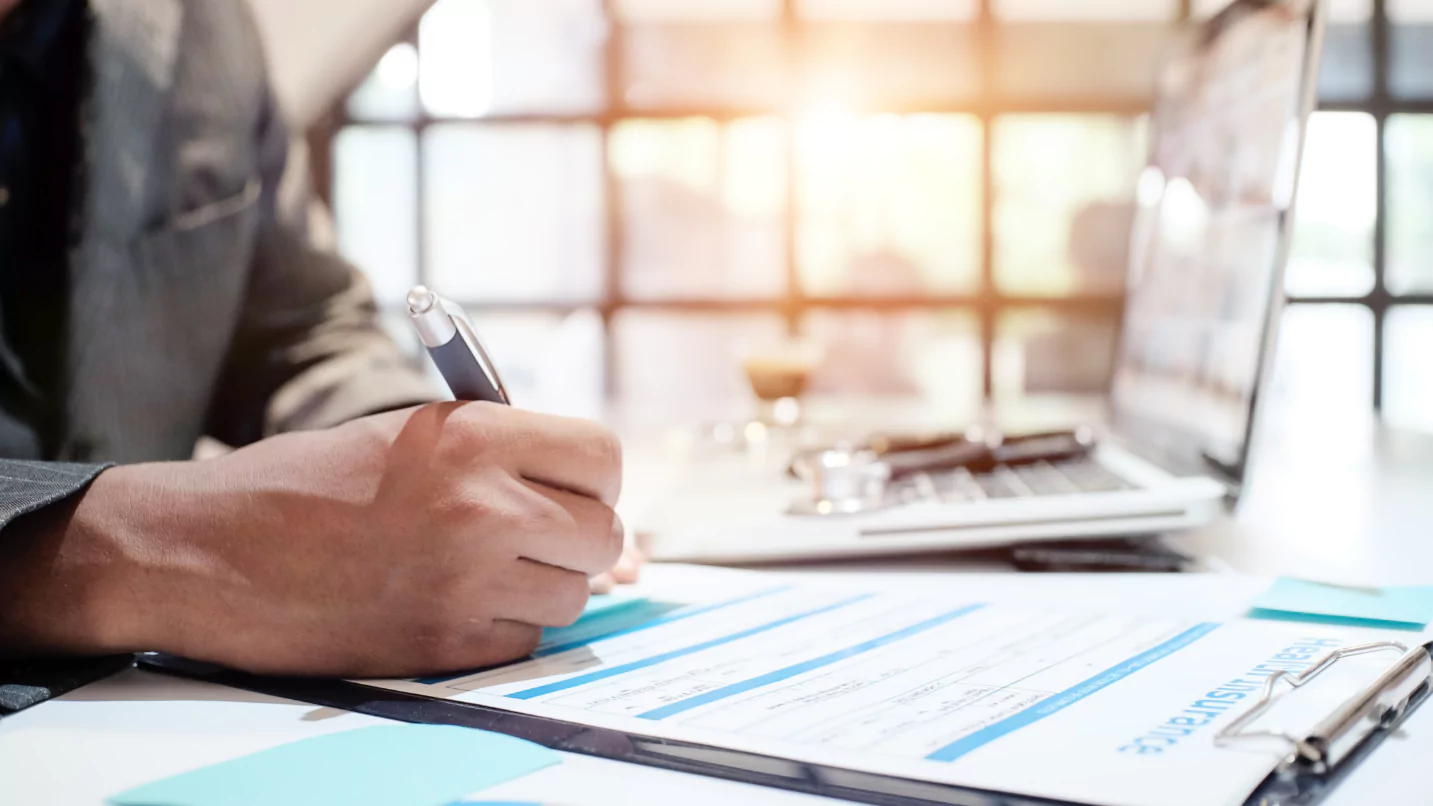 A man in a suit writing on a piece of paper for construction purposes.