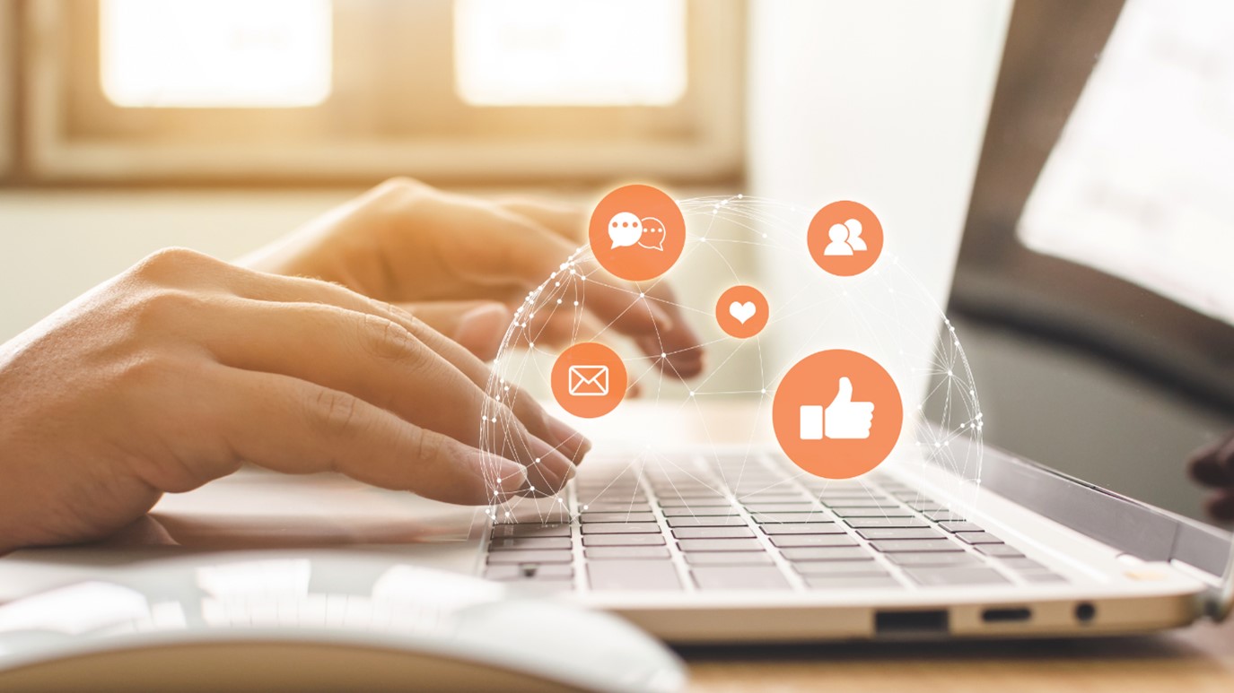 A person typing on a laptop with nonprofit icons on it.