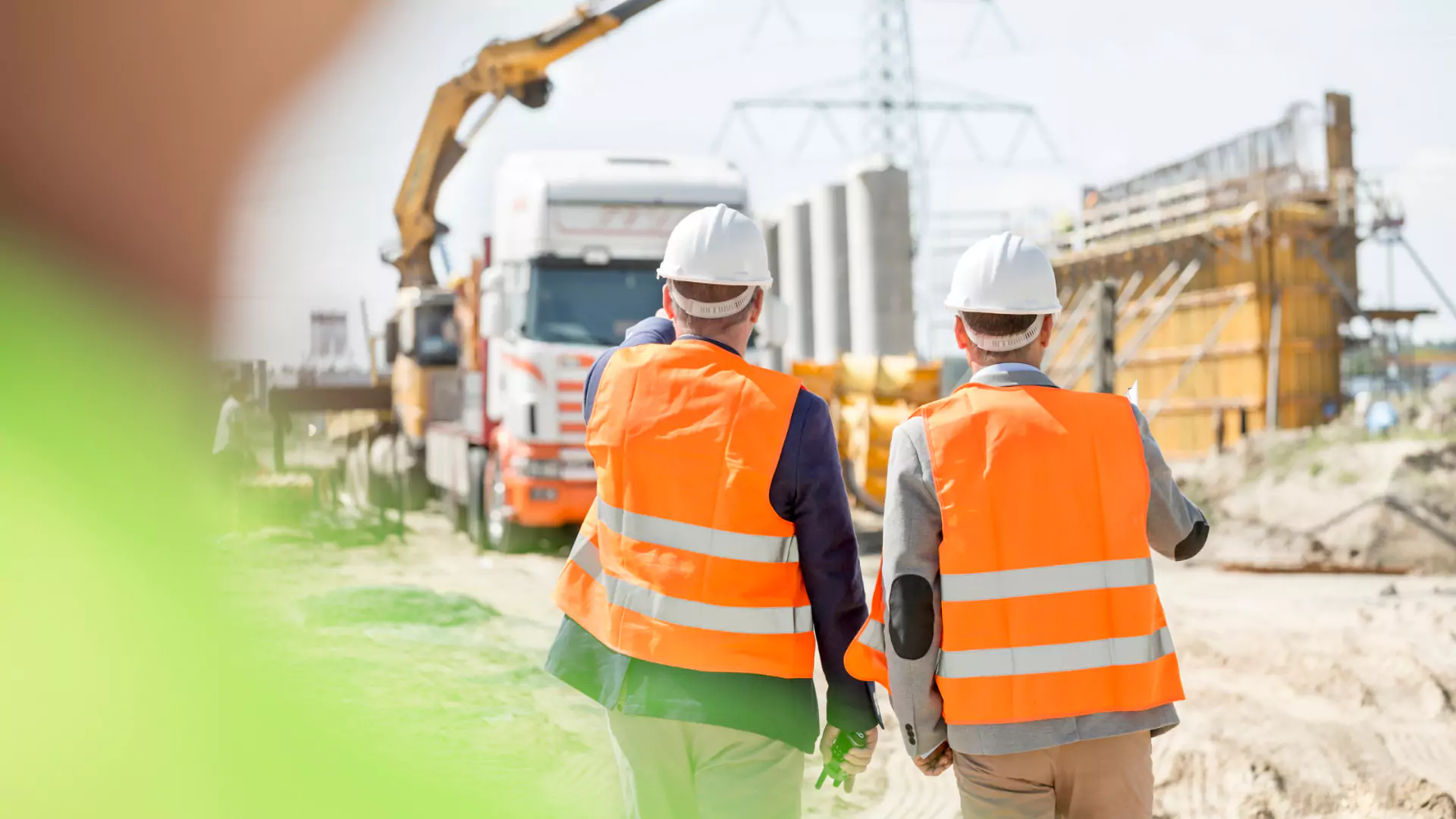 Two construction workers standing in front of construction equipment at a construction site.