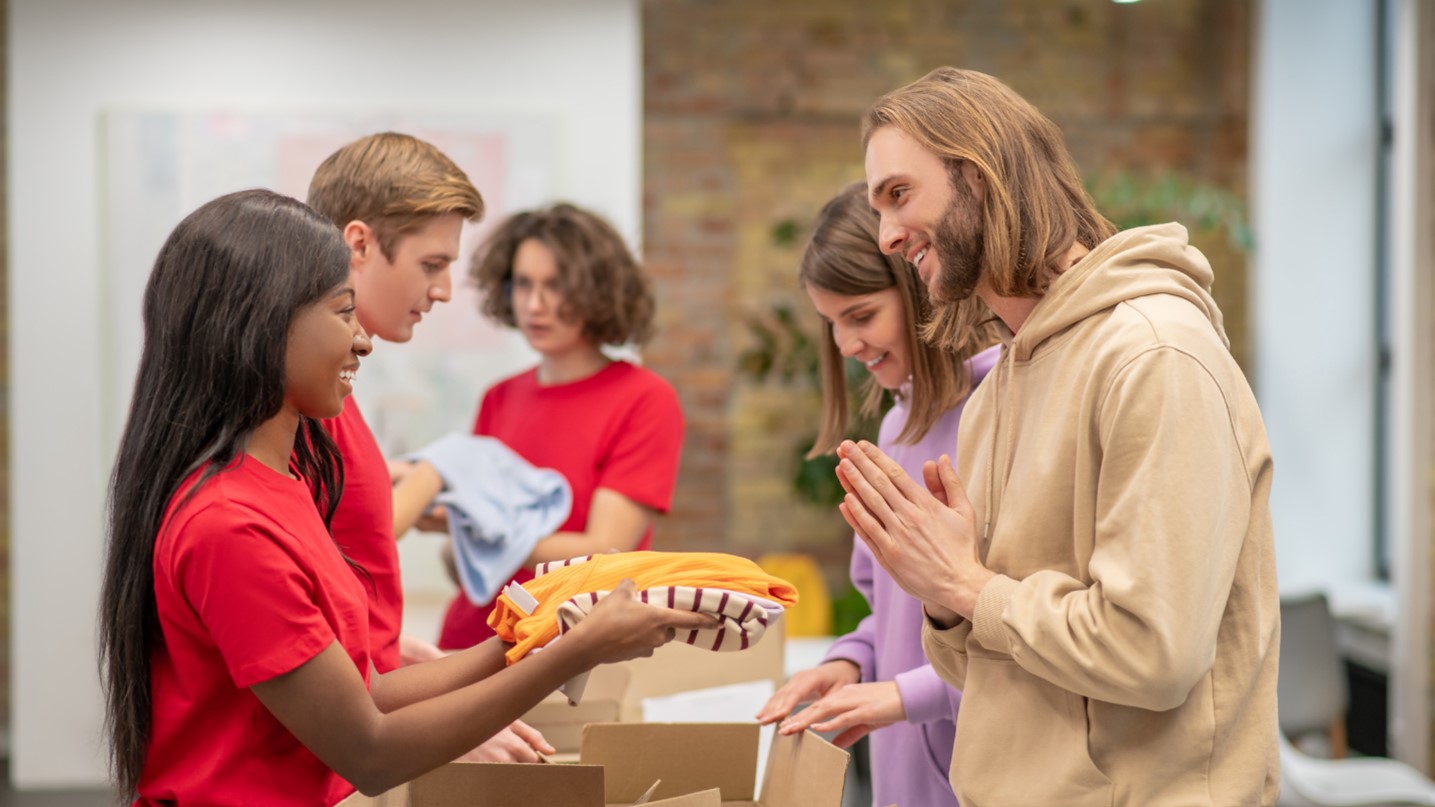 A group of people standing in a room with boxes, representing nonprofits.