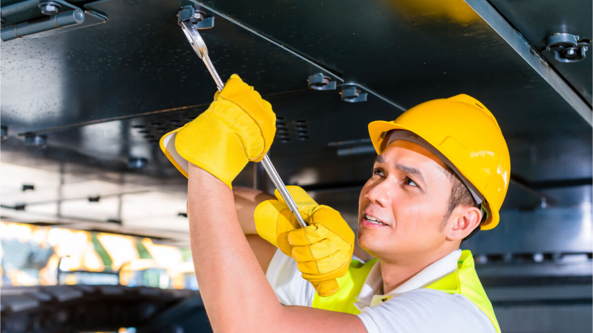 A person wearing yellow gloves and yellow vest holding a tool