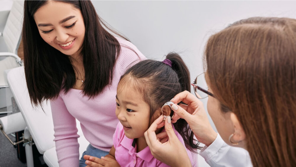 Doctor putting Hearing Aid to Child Patient