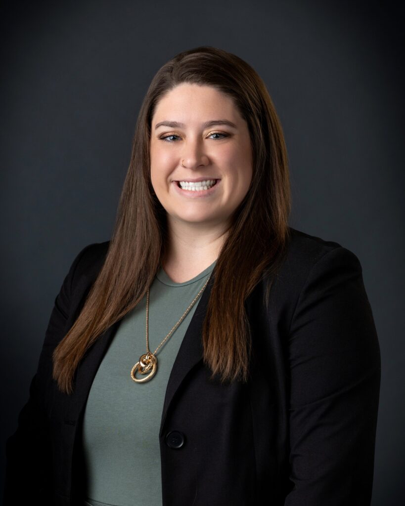 Professional headshot of Emmalee Dusanek, Certified QuickBooks ProAdvisor at MBE CPAs, smiling against a dark background.