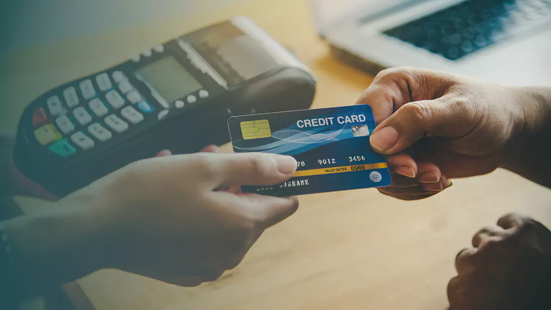 A person handing a credit card to another person