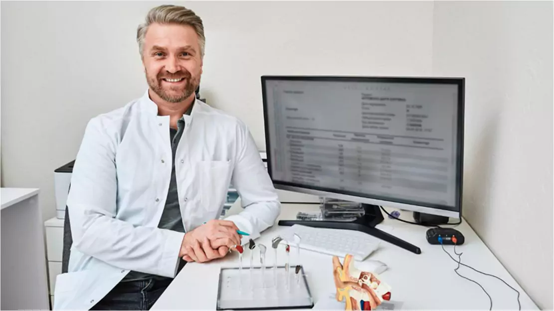A person sitting at a desk with a computer in White Coat