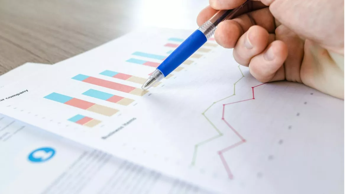 A hand holding a pen over a graph