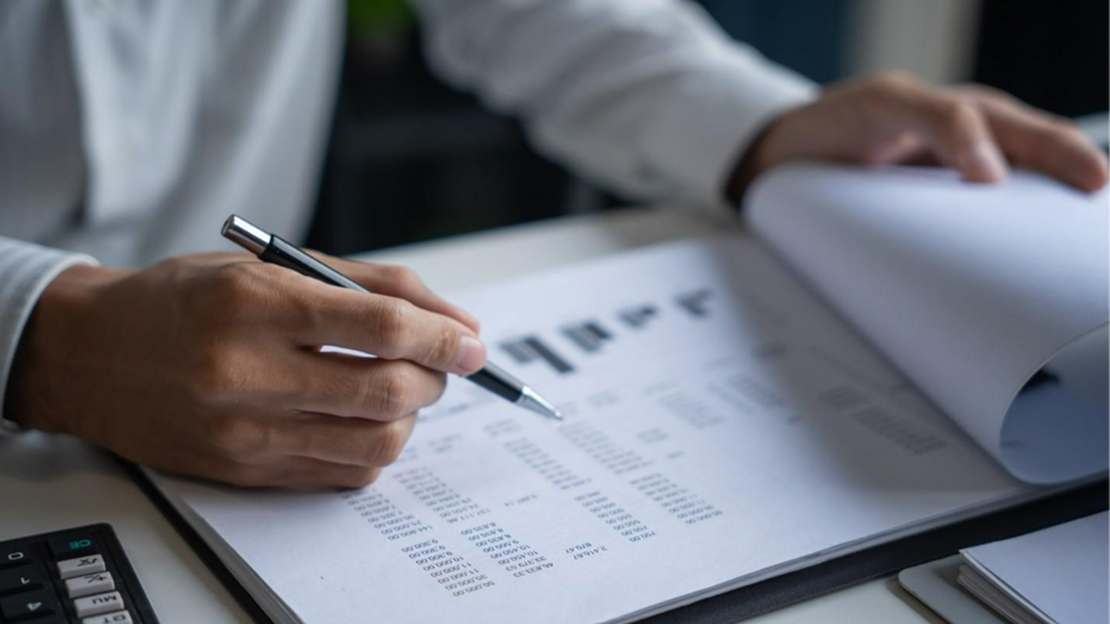 A person holding a pen and writing on a paper