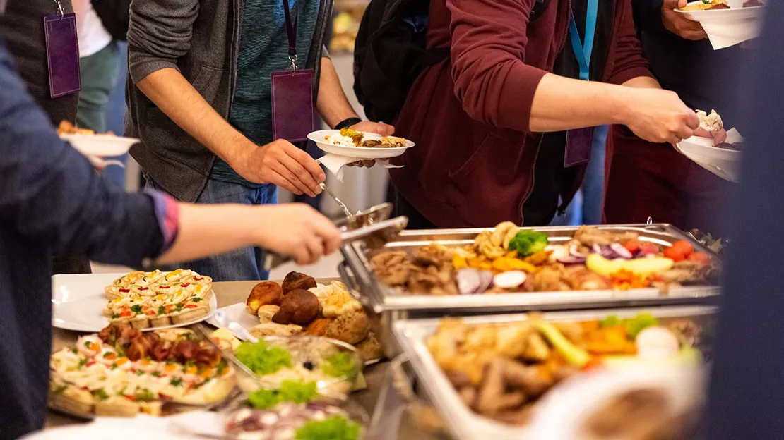 Foods on a tray and people getting food on their plates