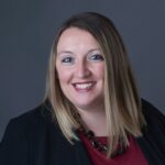 Professional headshot of Ashley Coy, at MBE CPAs, smiling against a dark background.