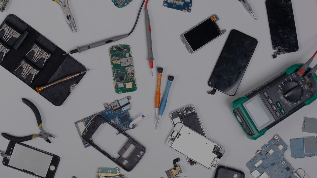 A desk covered with smartphones and electronic repair tools
