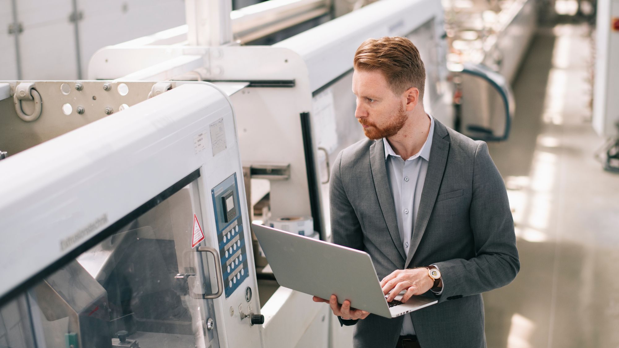 A man in a suit is standing while holding a laptop