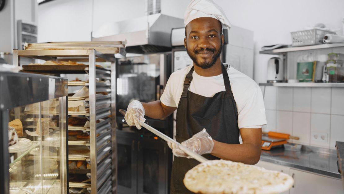 A Person Placing a Pizza Into the Oven Using a Pizza Peel