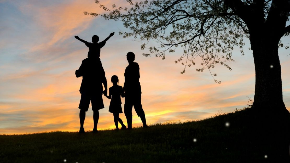 Family Standing Beside a Tree Agains the Sun