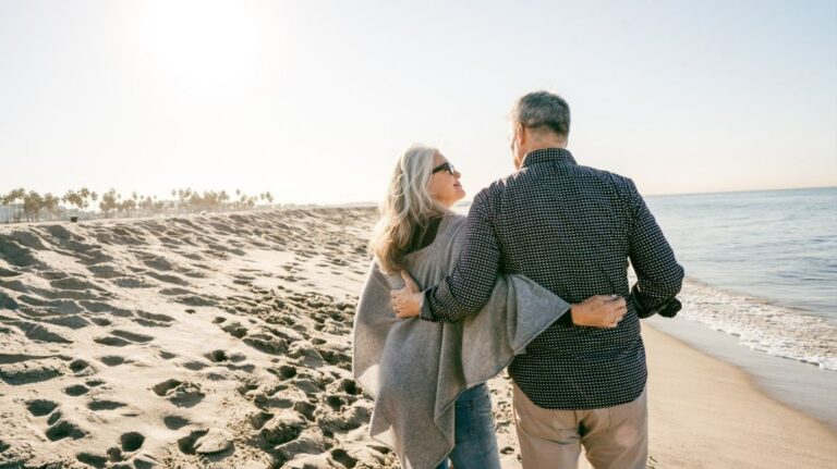 A couple is embracing each other while walking along the beach