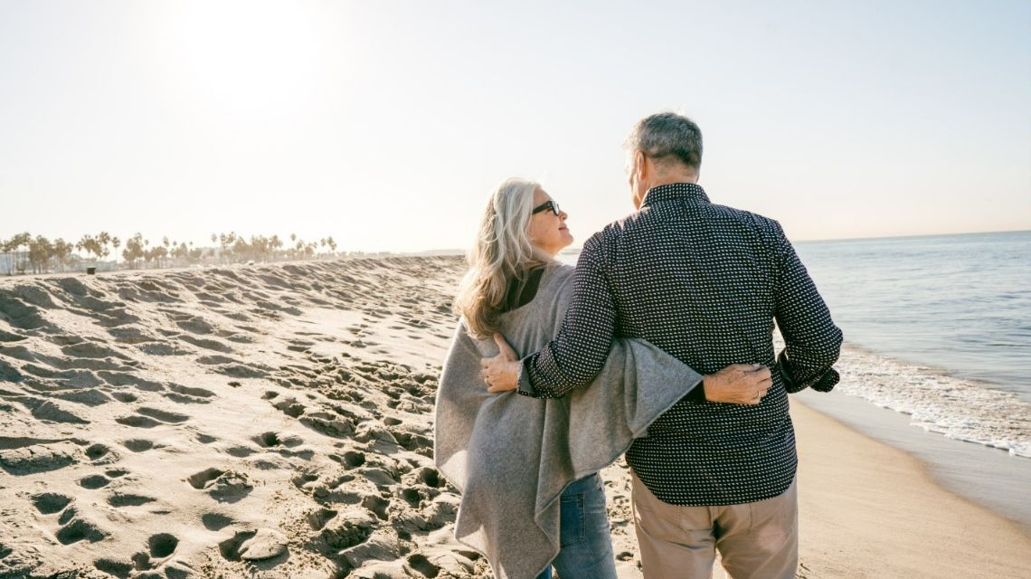 A couple is embracing each other while walking along the beach