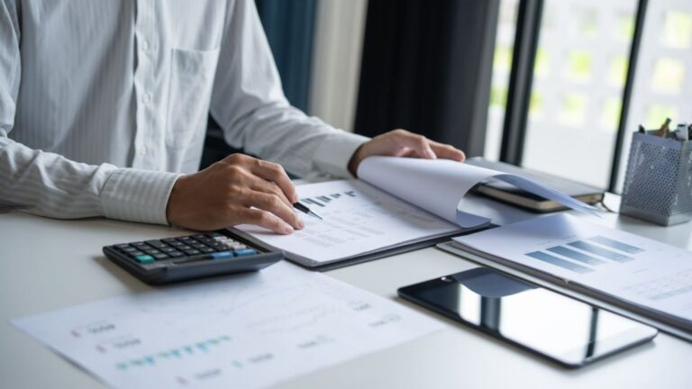 Half-body shot of an employee reviewing documents with a calculator