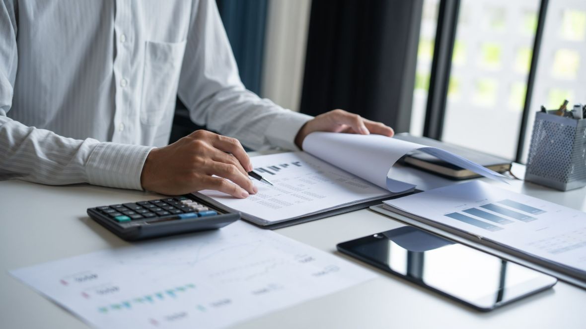 Half-body shot of an employee reviewing documents with a calculator