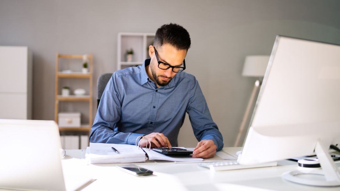 Man Using a Calculator on His Desk
