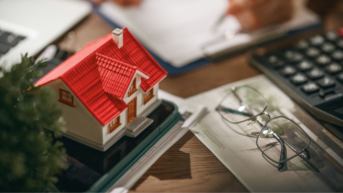 Miniature house model with eyeglasses beside it