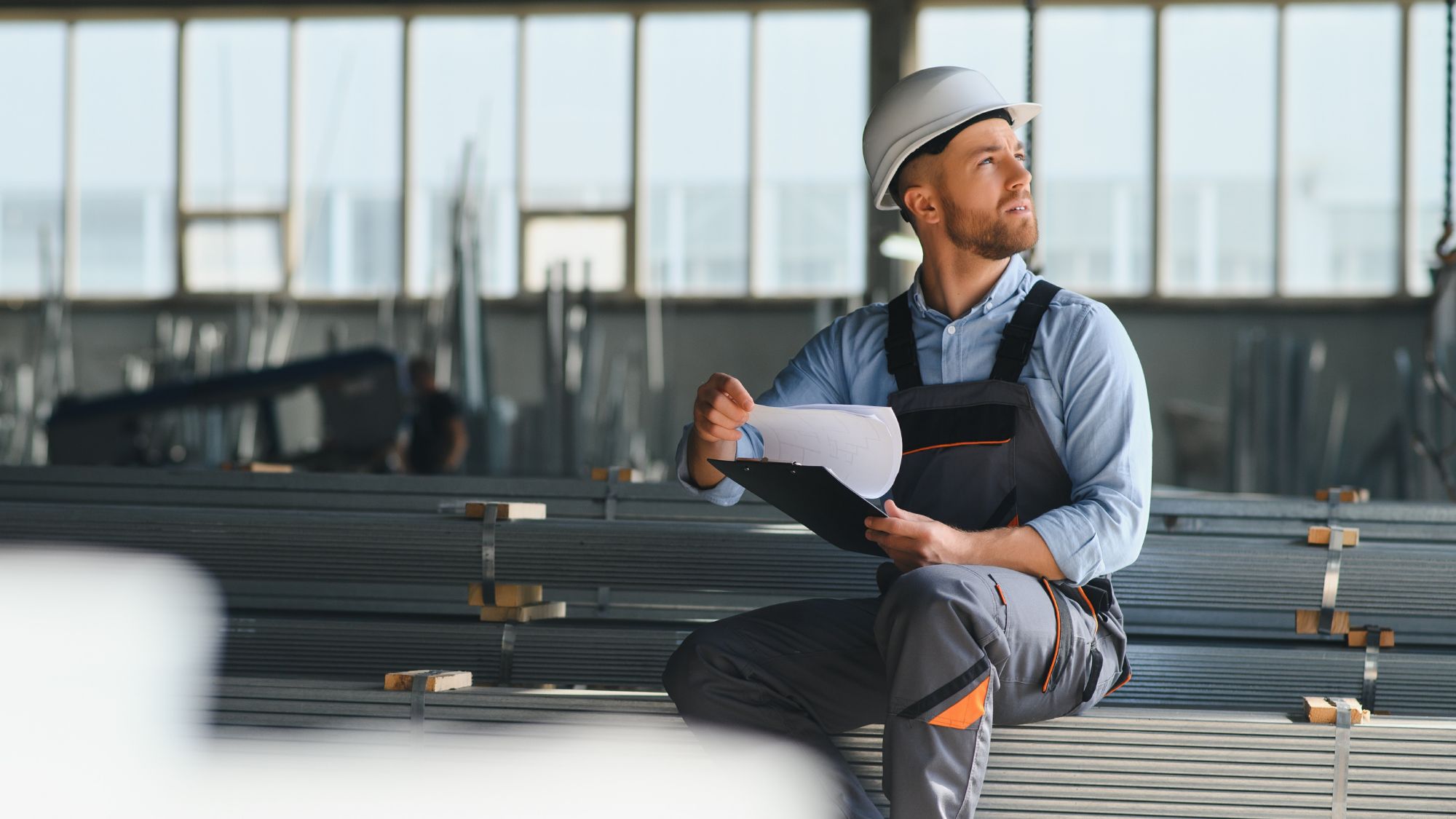 Man wearing a safety uniform holding a clipboard and looking up